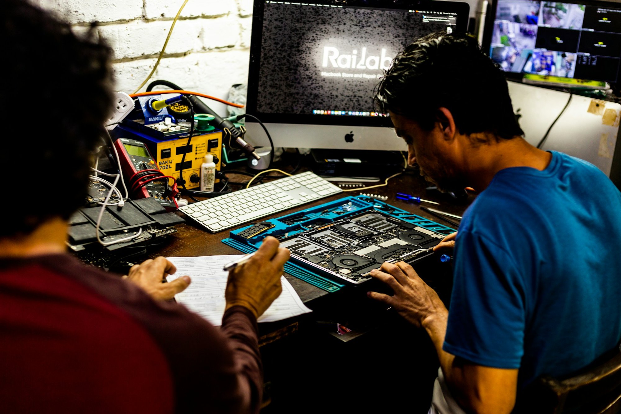 Two technicians repairing a computer at an electronics workbench