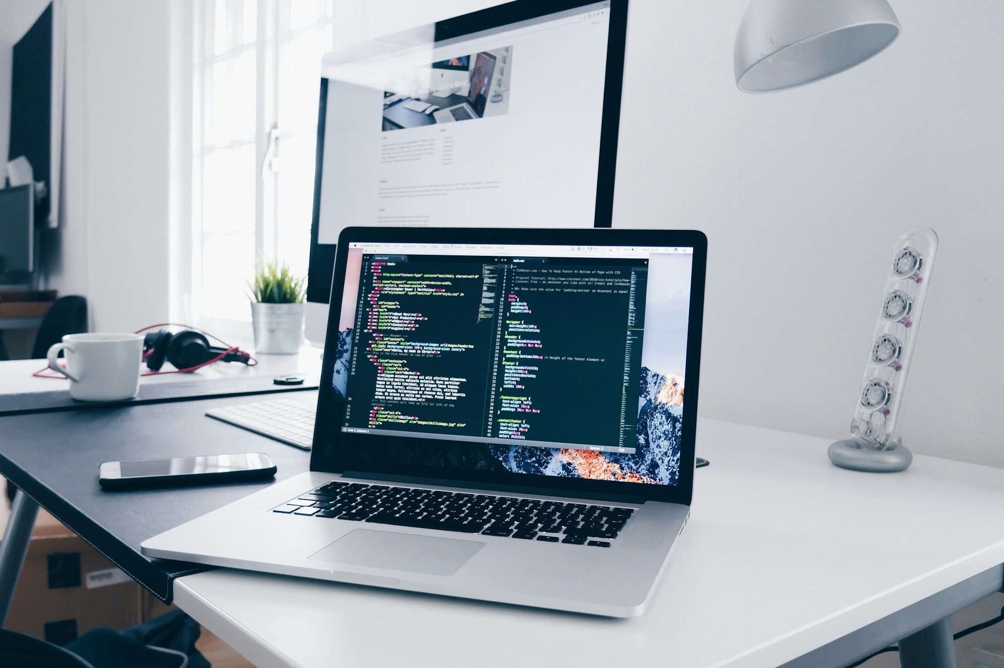 Code open in an editor on a laptop on a white desk