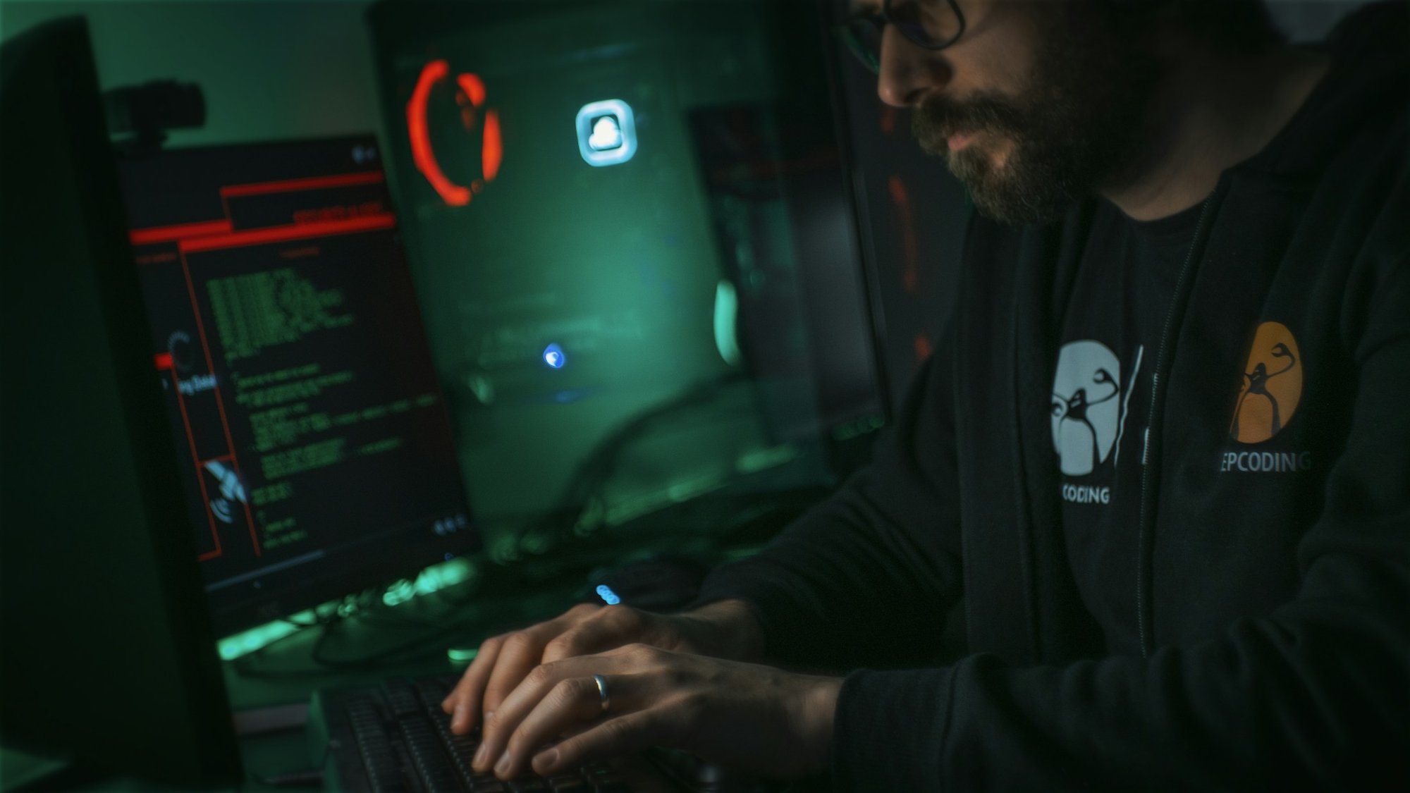 A security analyst working at a desk with several monitors