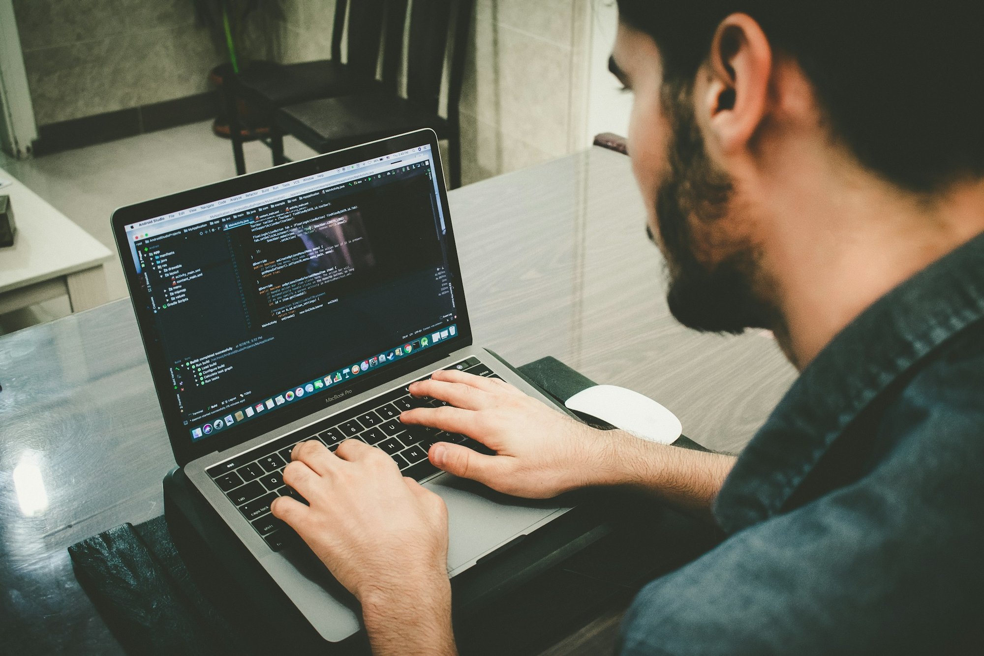 A man writing code on a laptop