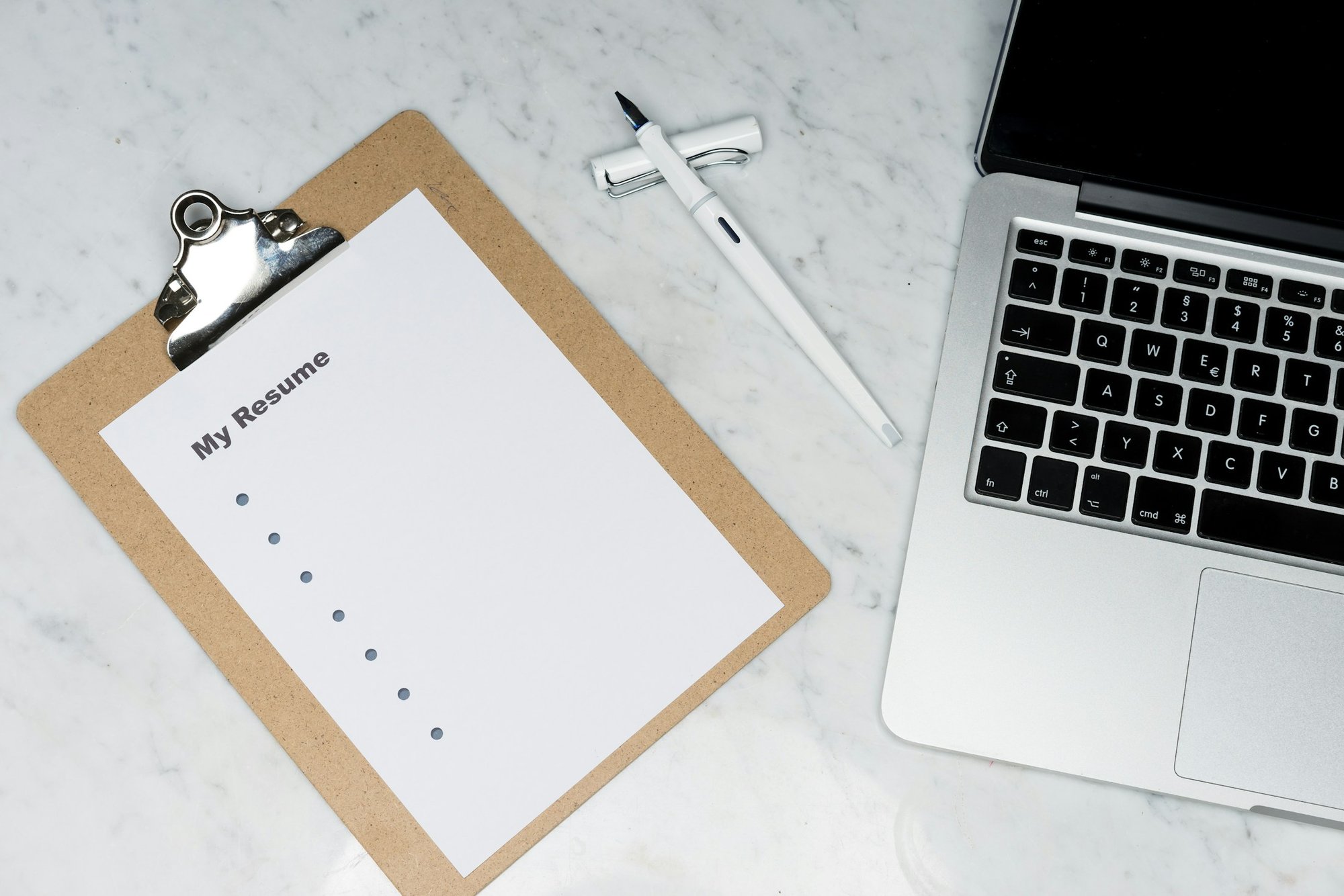 A clipboard with a resume next to a laptop