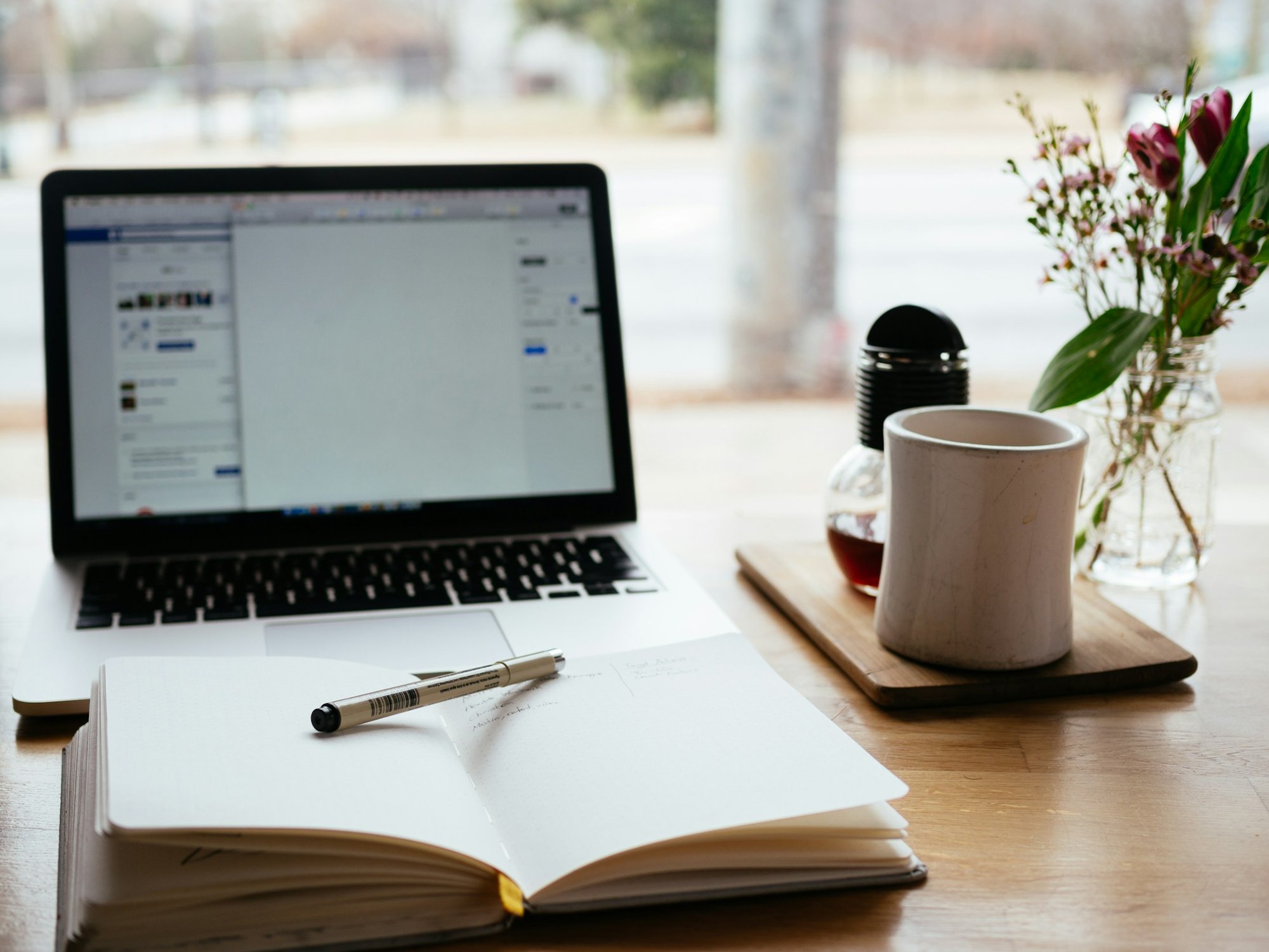 A laptop, notebook and coffee on a desk